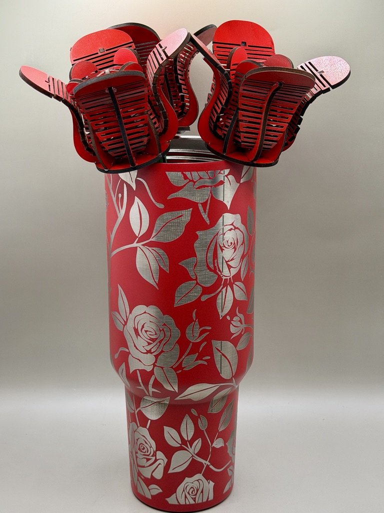 A tall, red vase with white floral and rose patterns, filled with multiple red and black plastic slotted seats stacked with backs facing upward.