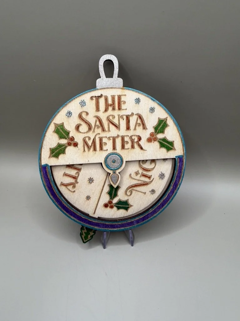 Decorative Christmas ornament shaped like a Santa Claus face with a clock face showing the holiday season, with holly leaves and berries.