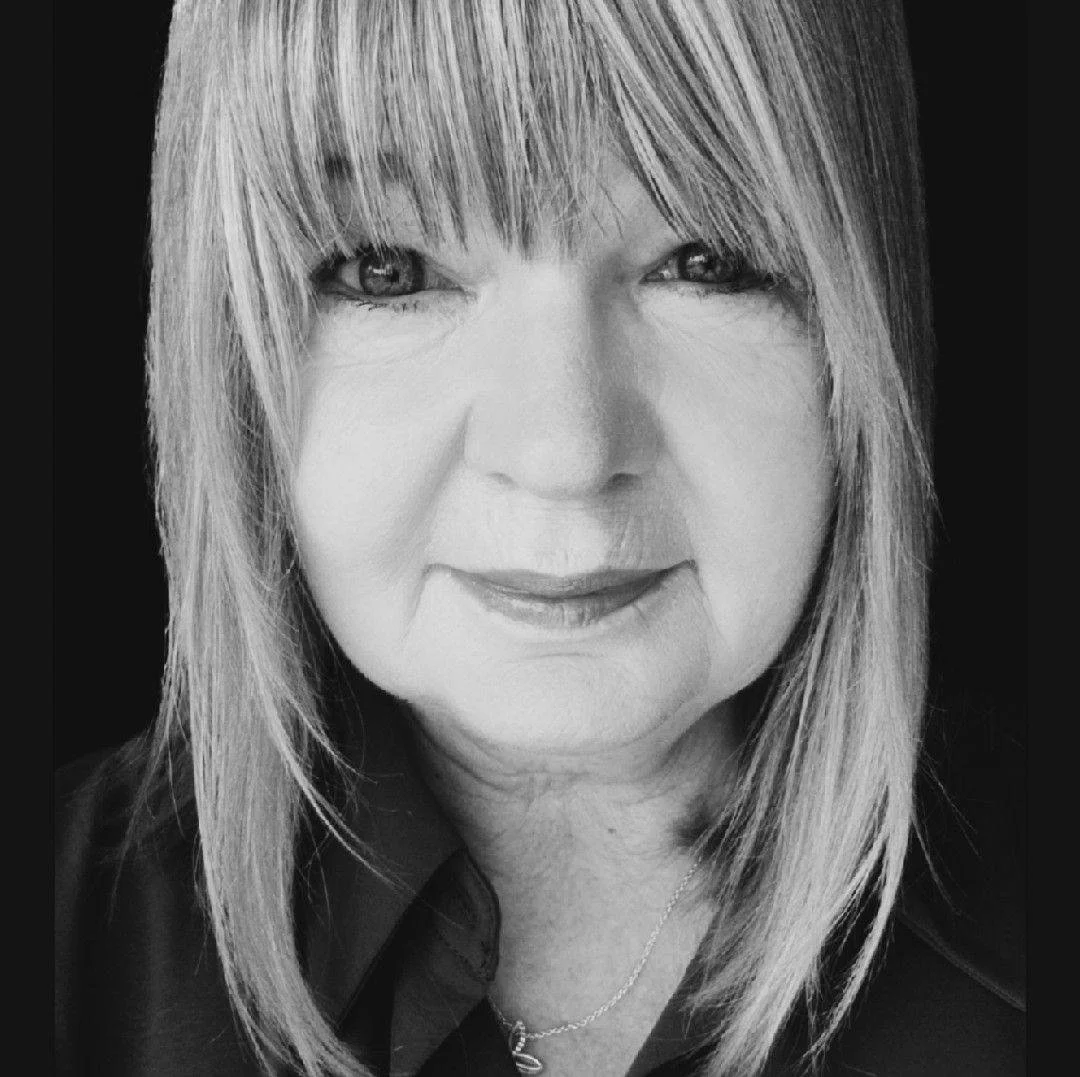A black and white close-up photo of a woman with shoulder-length hair and a gentle smile.