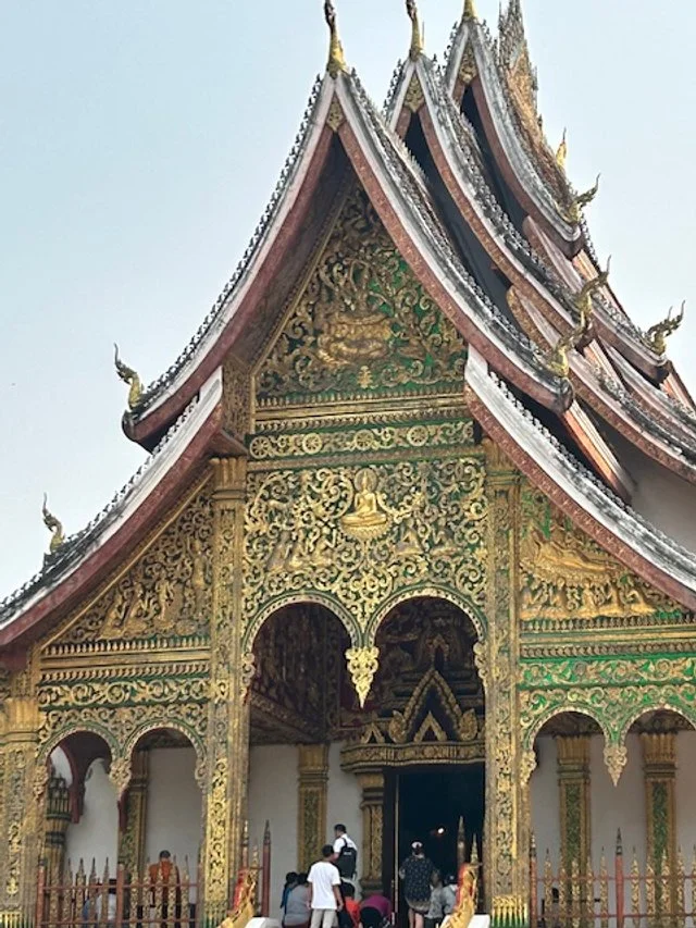 Traditional temple, Wat Xiengthong, with ornate gold and green decorations and a multi-tiered roof.