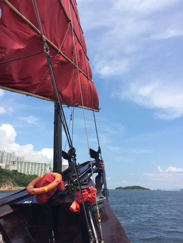 The Aqua Lung Boat to Stanley with a red sail on the water.