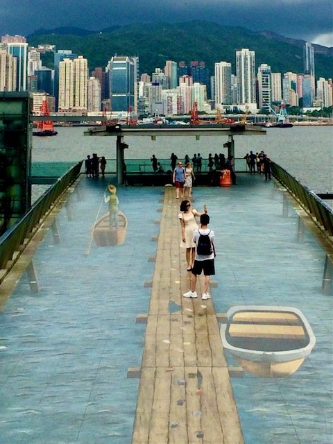 Street Art that looks 3D with the city skyline  in the background. Of boats on the water.