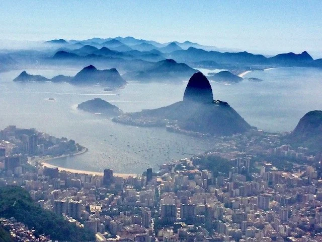 Aerial view of Rio de Janeiro with Sugarloaf Mountain, cityscape, and Guanabara Bay in the background.