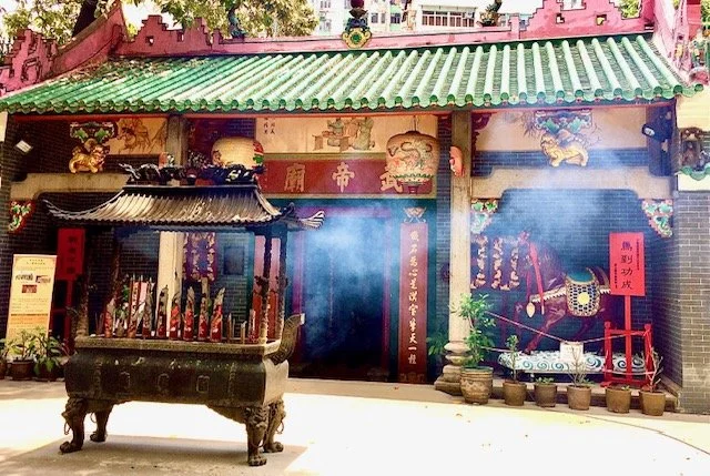 A traditional Chinese temple with ornate decoration, incense burning in a large incense burner, and lanterns hanging on the building's facade.