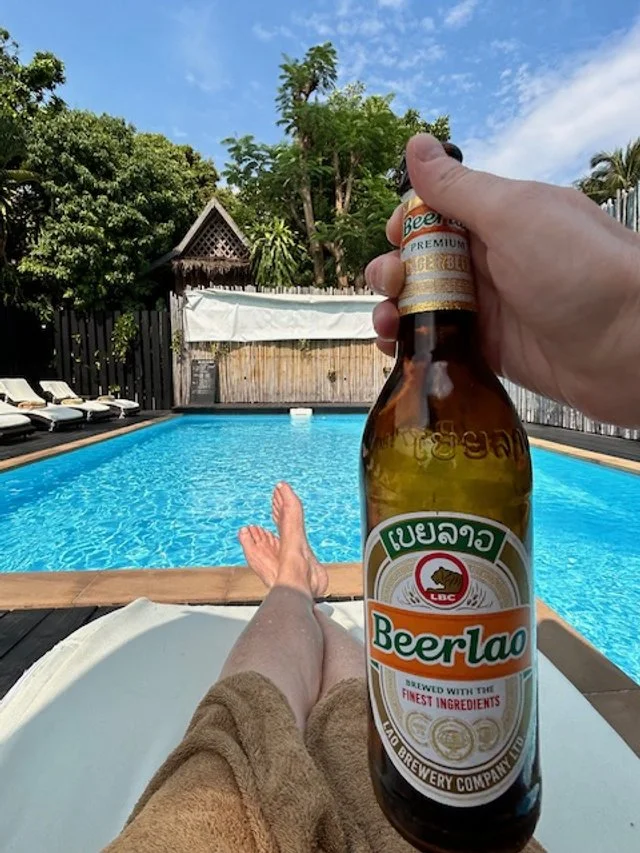 OBT time for a break! At the swimming pool, holding a beer bottle labeled 'Beerlao,' at the Sanctuary Hotel, Luang Prabang