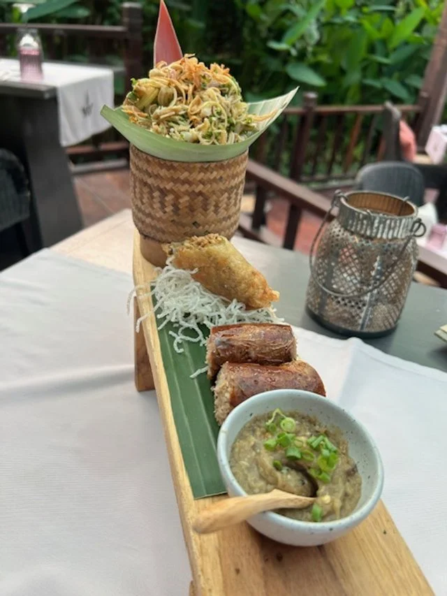 A wooden serving platter with various Asian dishes. Manda de Laos tasting first course