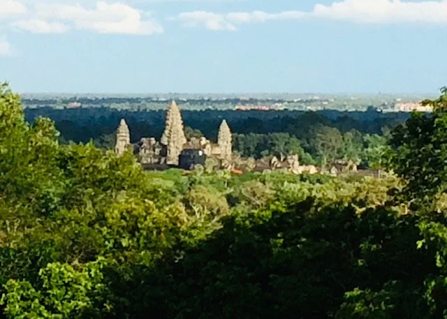 View of Angkor Wat temple complex seen through trees.