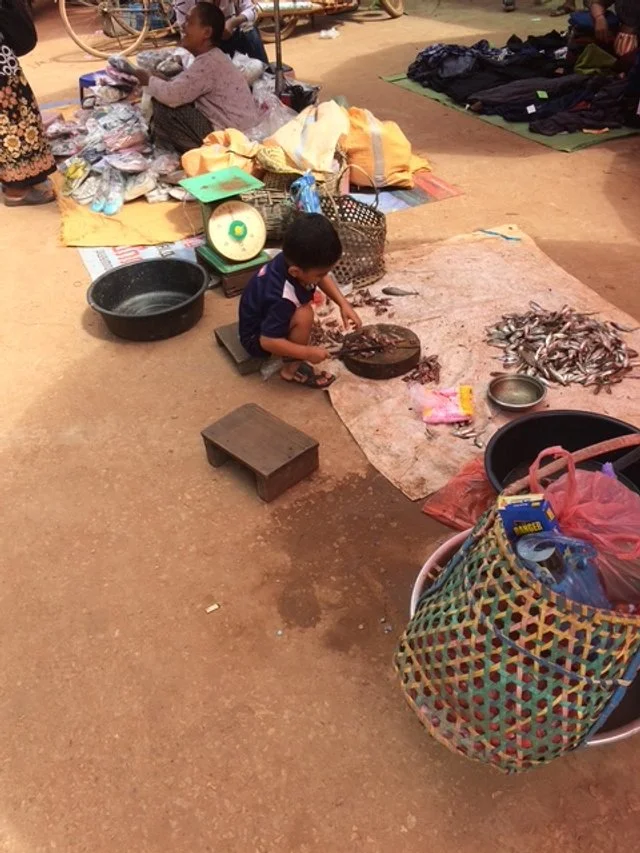 Kid with a machete cutting fish up at the Local Market