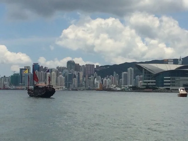 View from Hong Kong Harbor with city skyline and a mountains in the background.