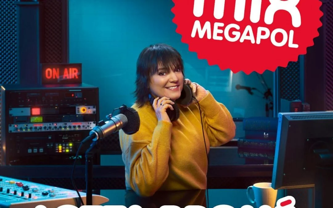 En kvinna i en radiostudio som pratar i telefoner, omgiven av radioutrustning och ett datorbord.