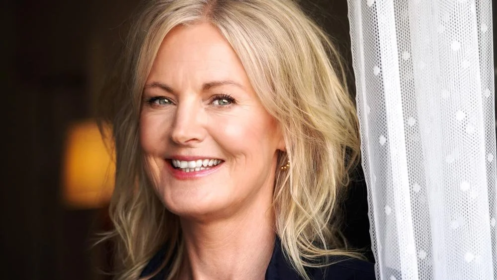 Karin Otterbjörk ler bredvid en gardin