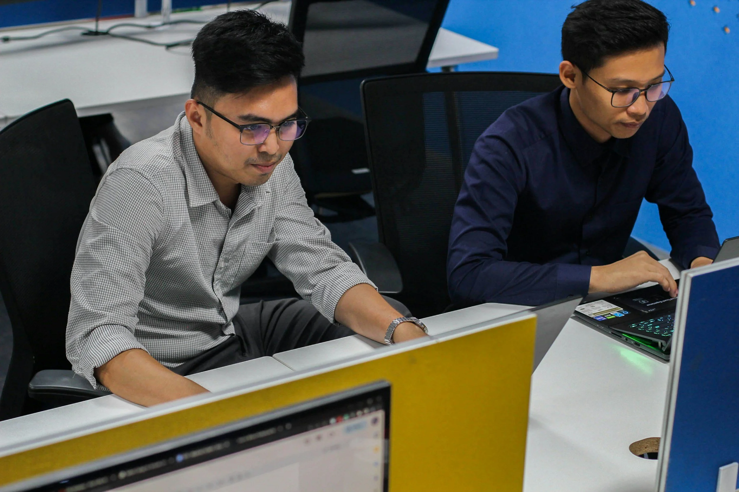 Two men working on computers in an office.