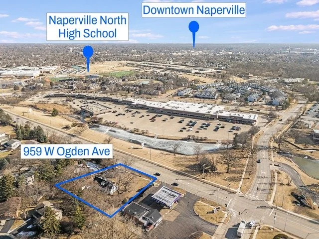 Aerial view of a neighborhood with labeled locations including Naperville North High School, Downtown Naperville, and 959 W Ogden Ave, showing a mix of residential and commercial areas, parking lots, and roads.