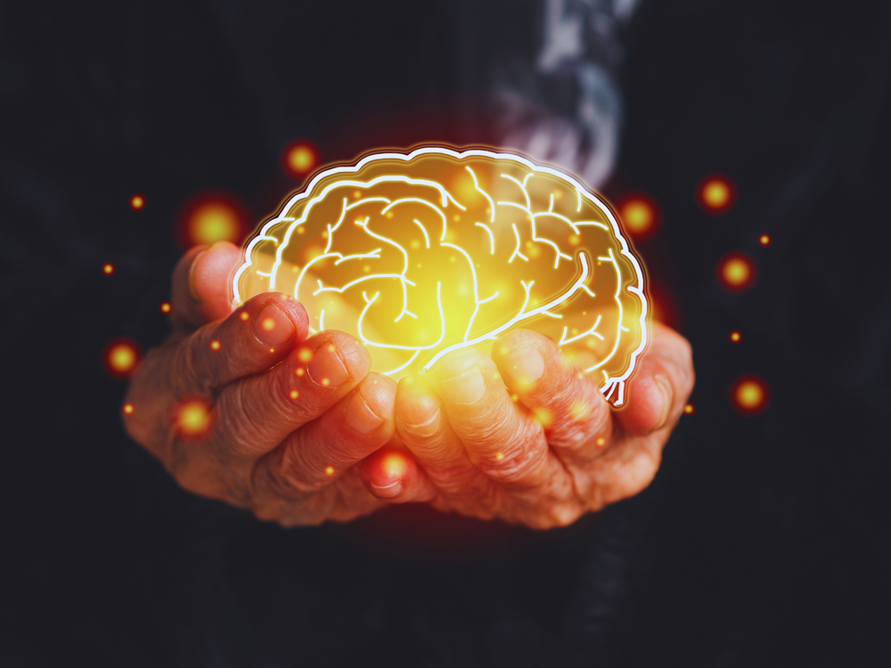 A glowing digital illustration of a human brain held in elderly hands, representing neurological care