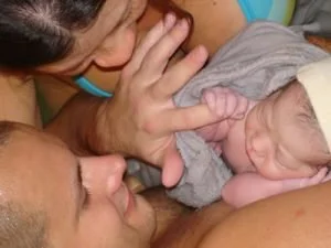 A woman and a man holding a newborn baby.