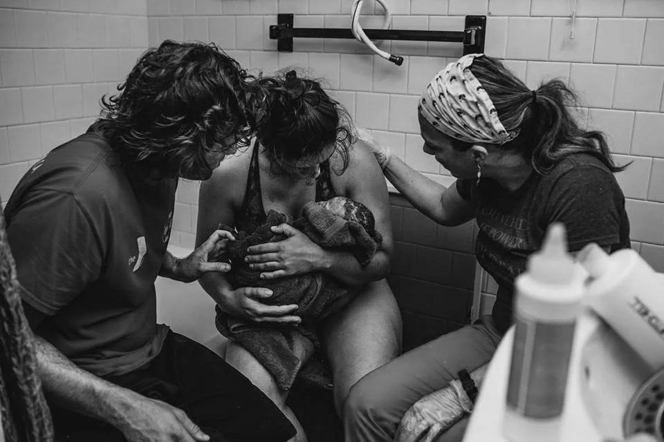 A close-up black-and-white photo of a newborn baby sleeping, wrapped in a blanket.