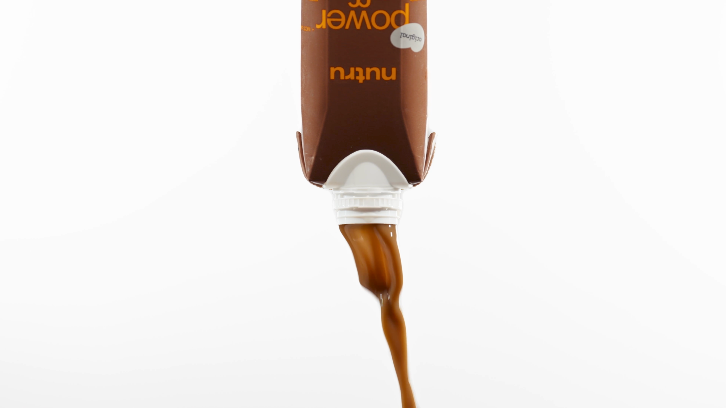 Chocolate syrup being squeezed from a squeeze bottle against a white background.