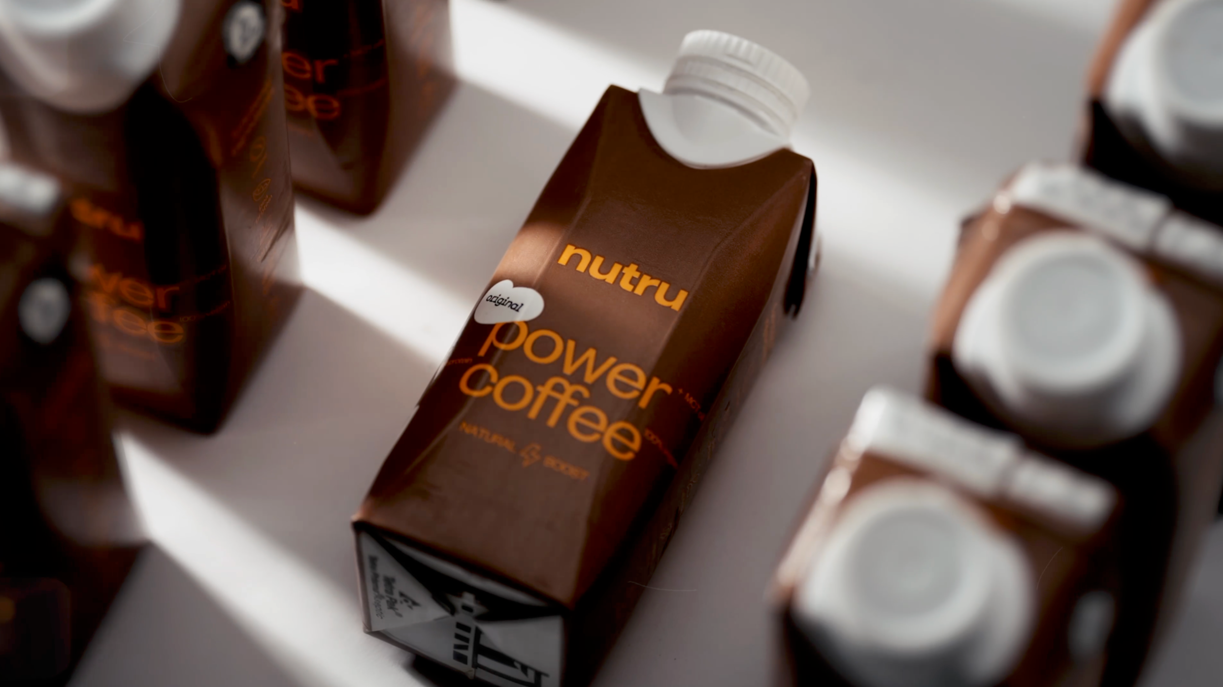 A carton of Nutru Power Coffee on a white surface surrounded by other similar cartons.