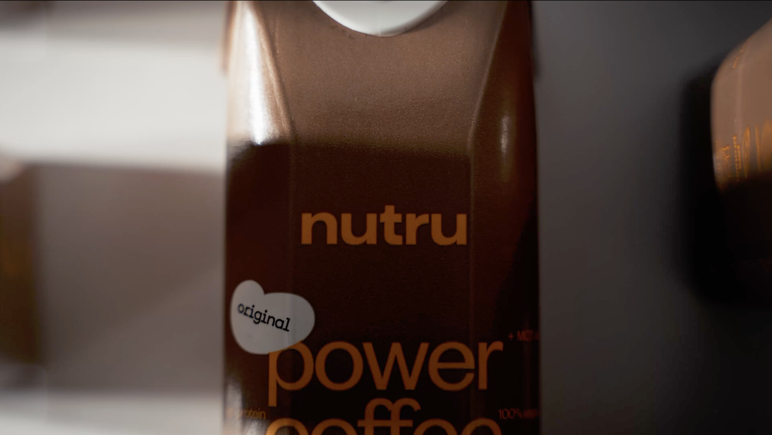 Close-up of a Nutru Power Coffee carton with a white heart-shaped label that says 'original' on a dark background.