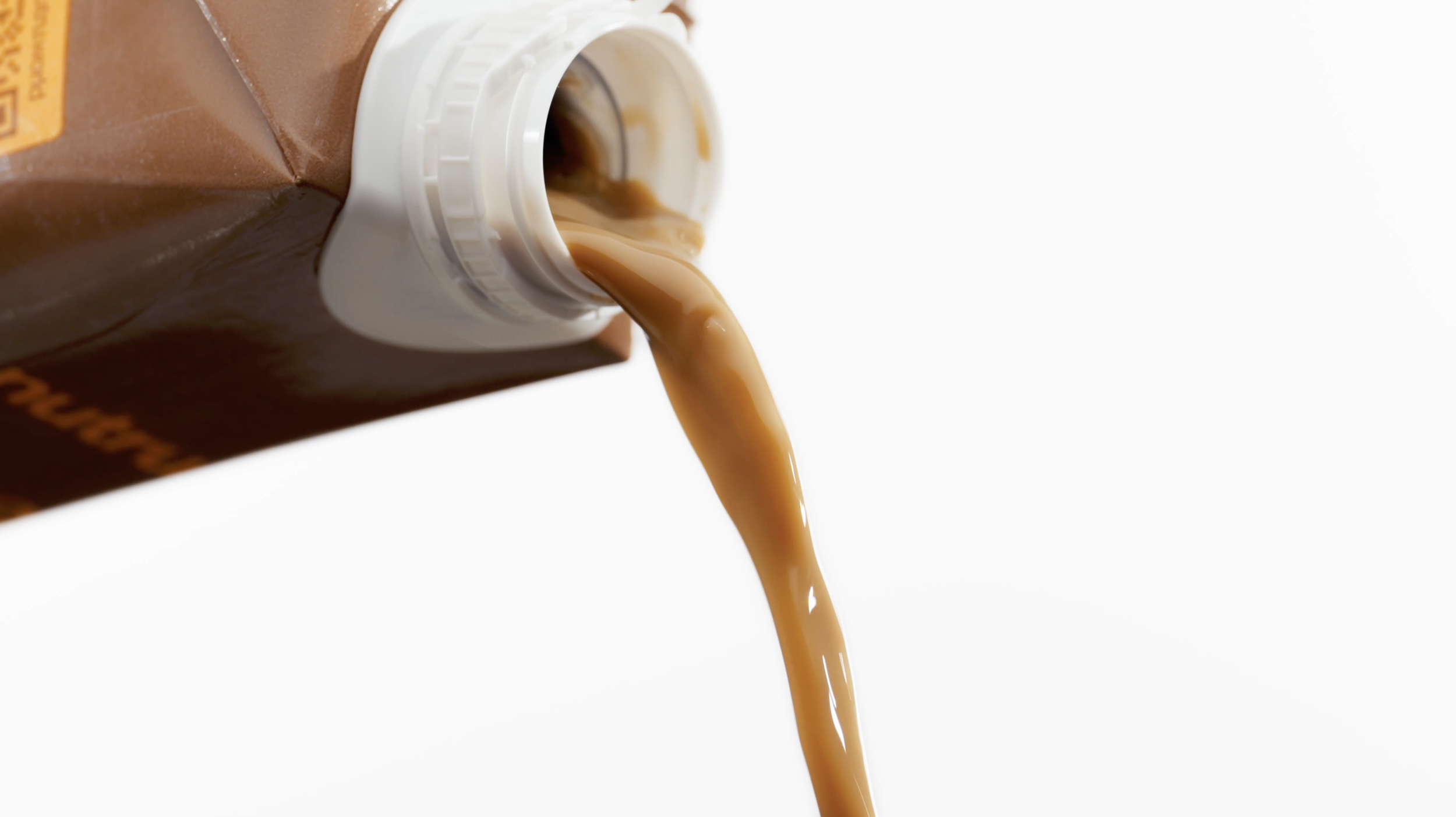 Coffee is being poured from a bottle into a white mug, with a white background.