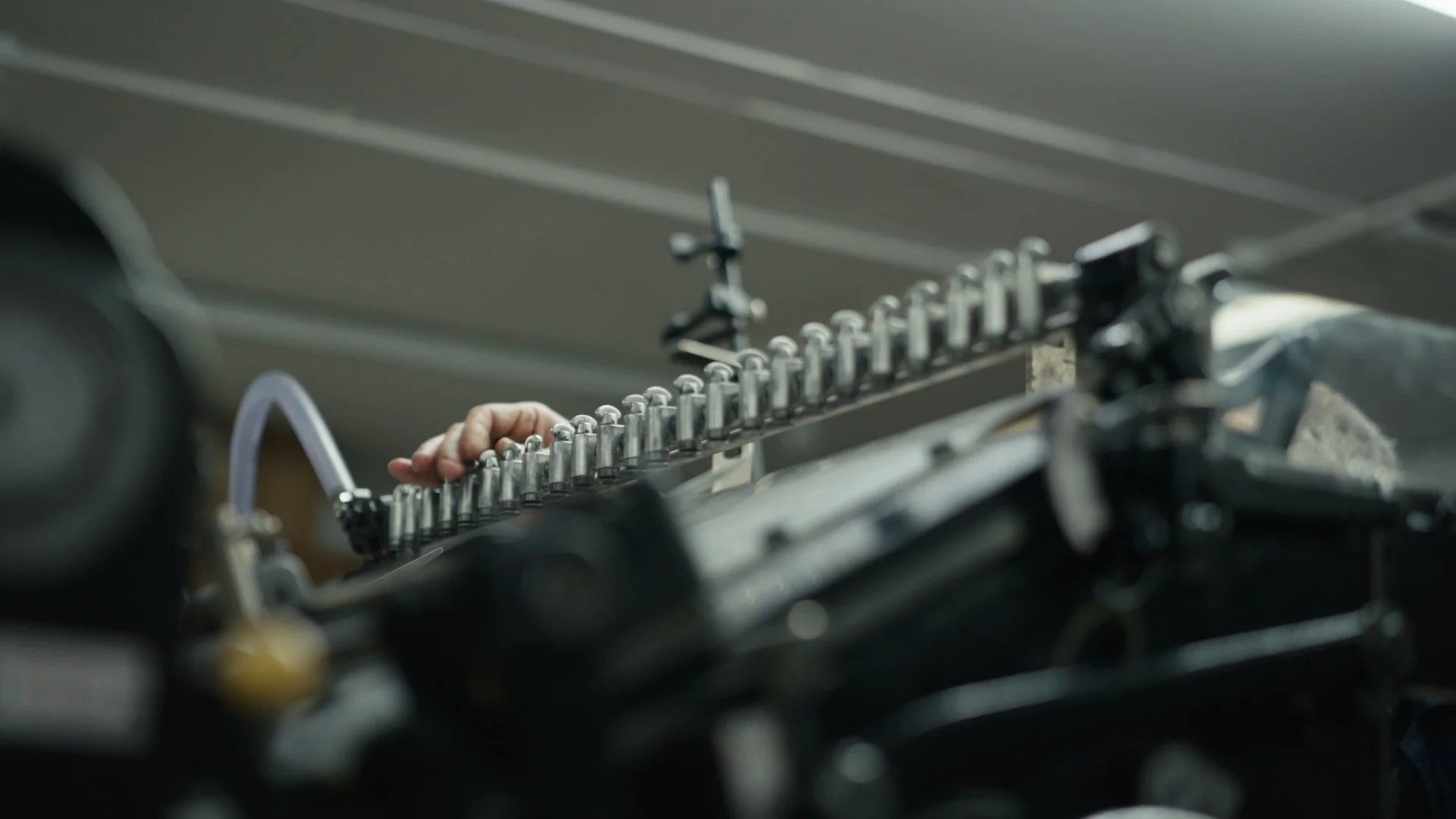 A close-up view of a row of metal bullets on a machine gun, with a person's hand adjusting the gun in the background.