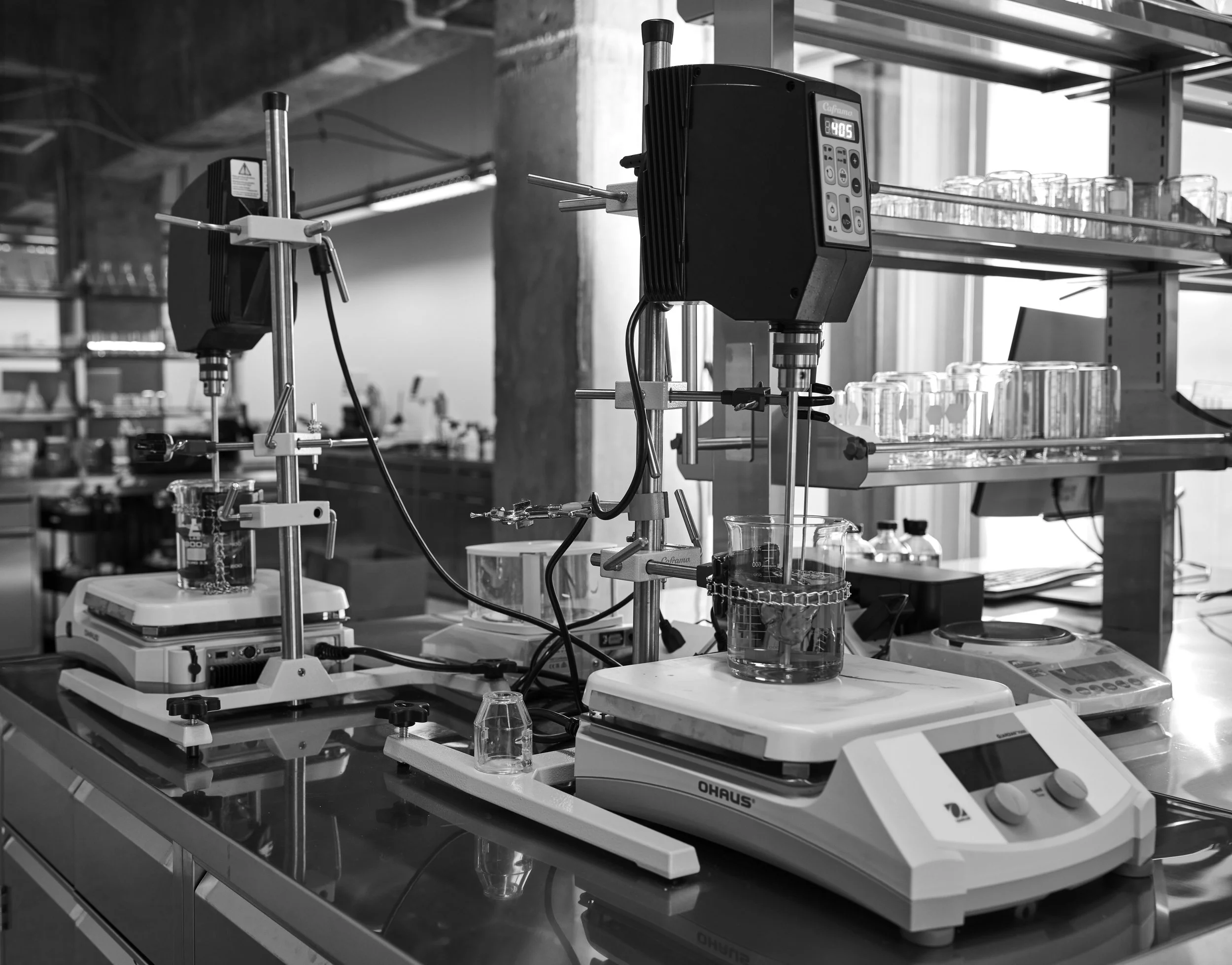 Laboratory setup with scientific equipment, including a stirring device, heating plates, and glass containers for experiments.