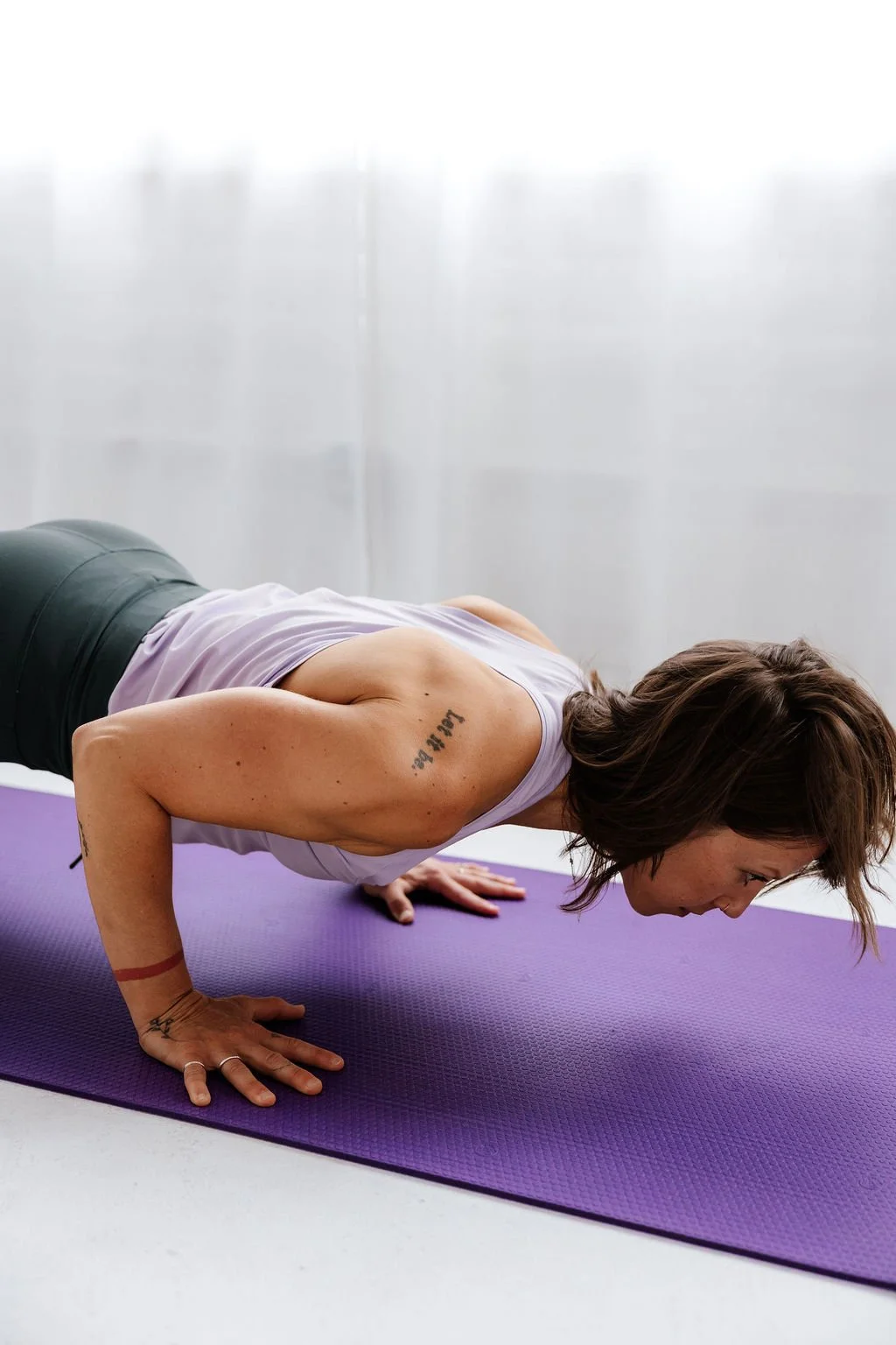 Woman in her 40s demonstrating mindful strength training and mobility work on a yoga mat — part of hormone-adapted training for peri-menopause and menopause.