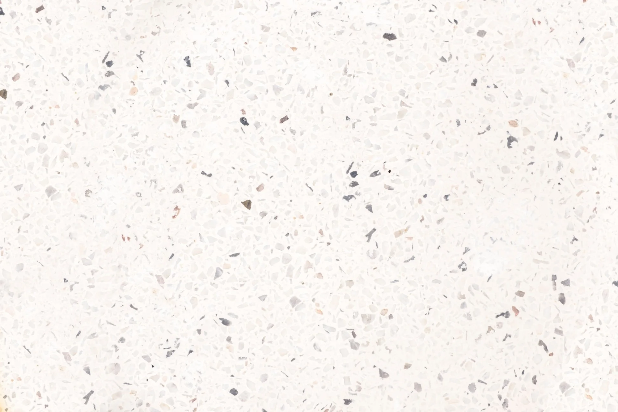 Close-up of a white paint or terrazzo surface with small, scattered gray and black speckles.