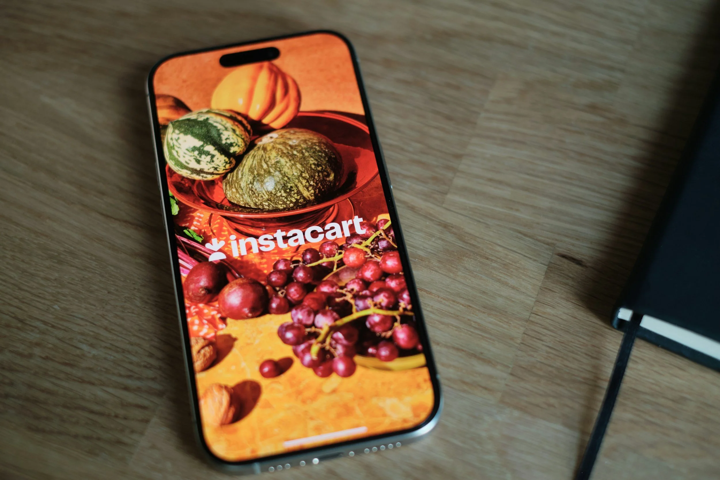 Instacart logo with fruit in the background on a phone screen.