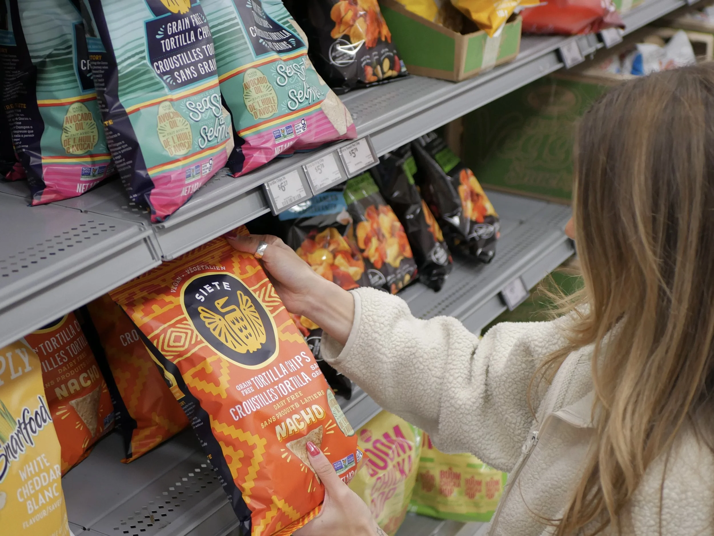 Woman holding a bag of chips in a grocery store aisle