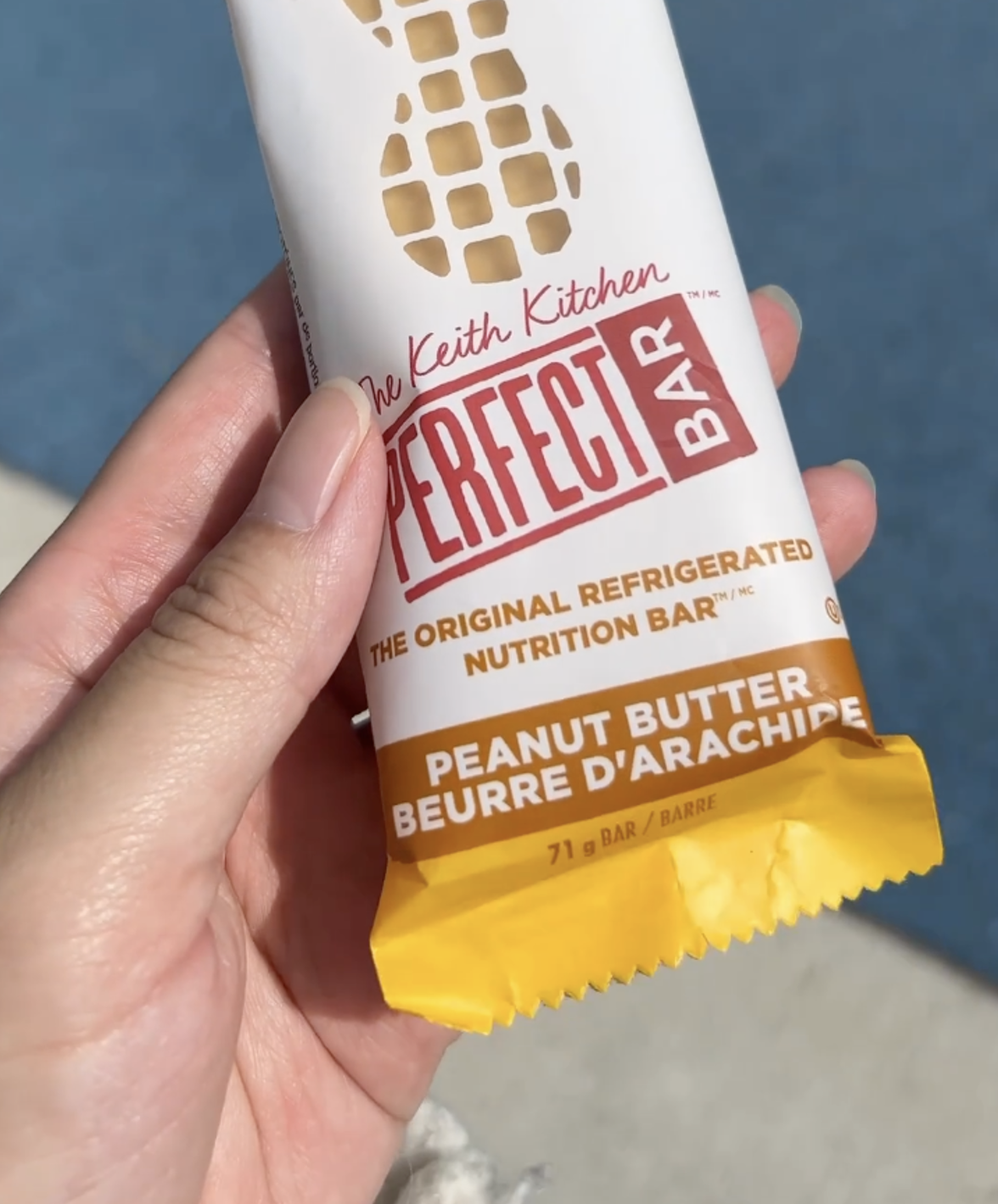 A hand holding a Perfect Bar protein bar.