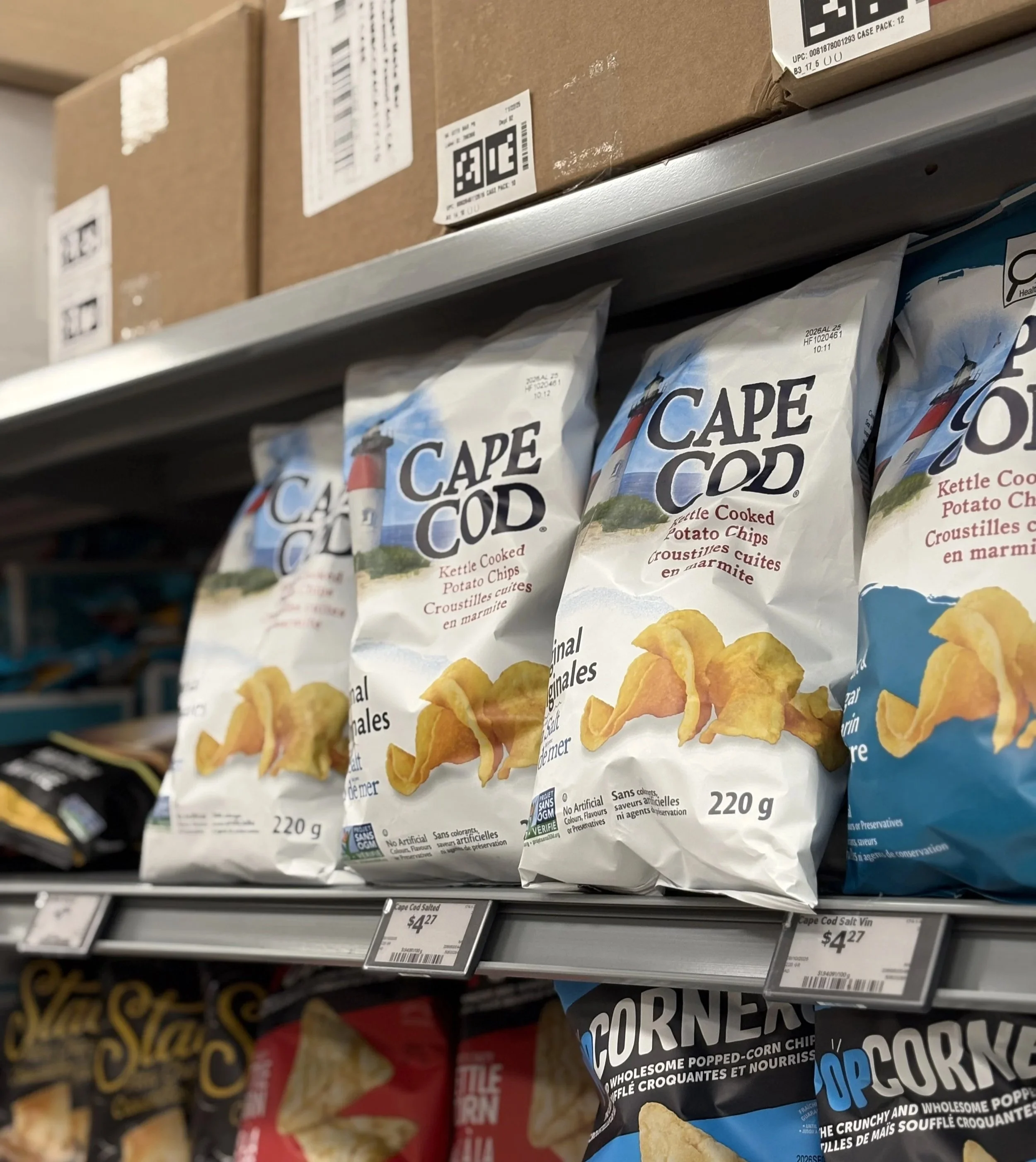 Hand grabbing a loaf of bread off of a grocery store shelf.