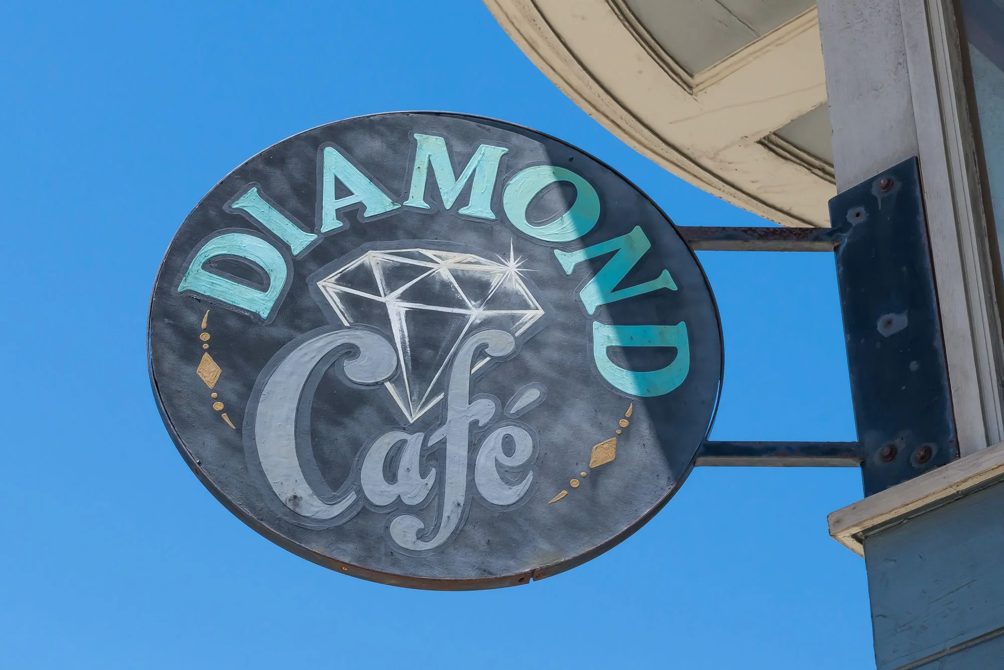 Sign for Diamond Café with a diamond illustration against a blue sky.