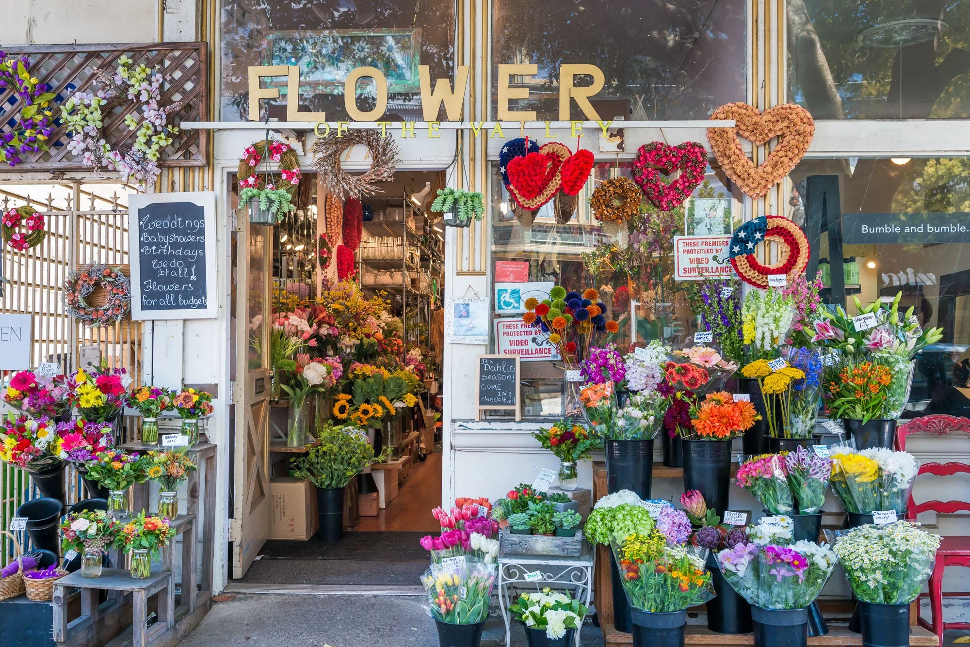 Flower shop entrance with colorful floral arrangements and decorative wreaths.