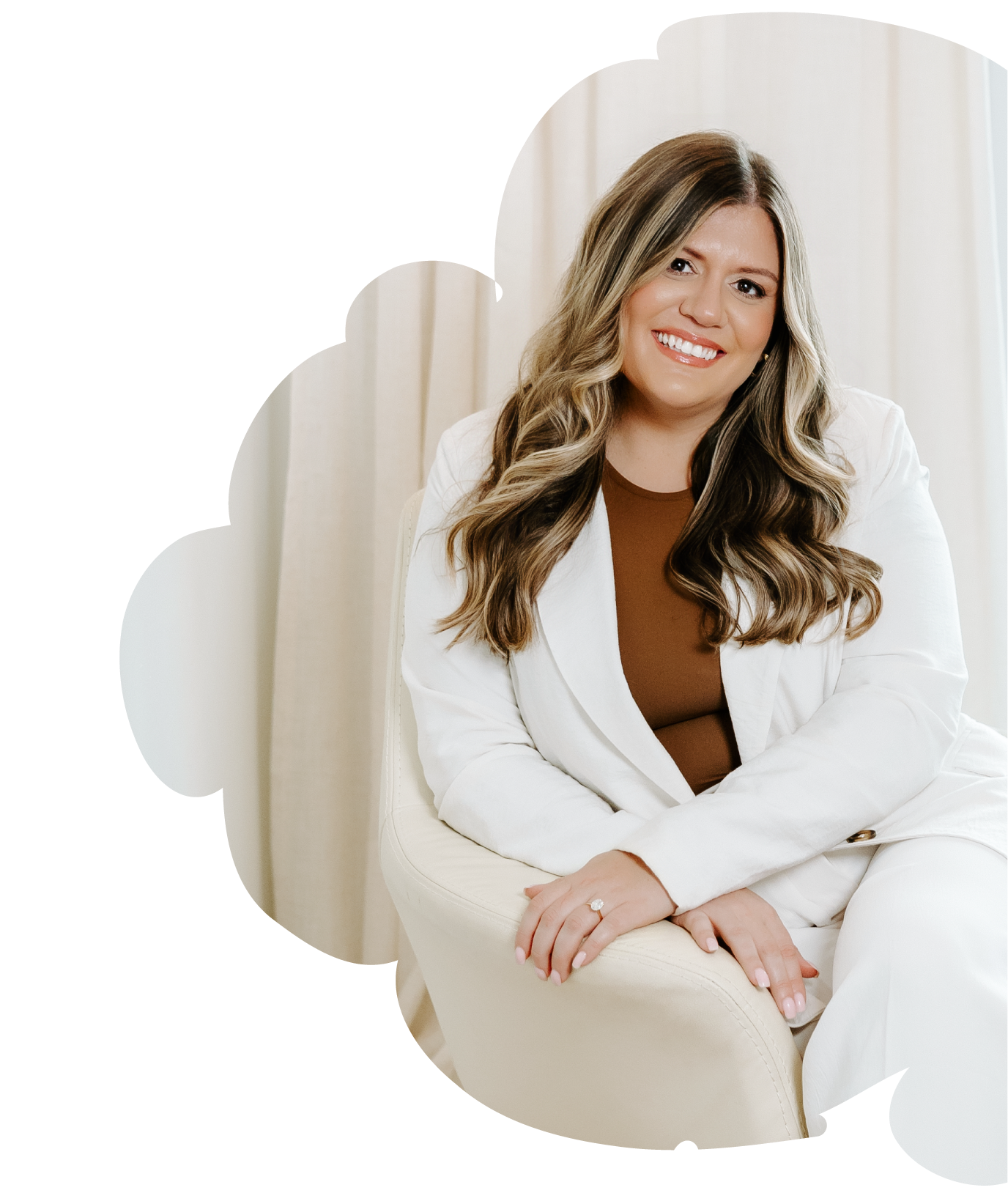 Heather Gorr, LPC-S, trauma-informed therapist and clinical supervisor based in Austin, Texas | Woman with dark curly hair smiling, wearing a white suit and brown shirt, sitting on a white chair