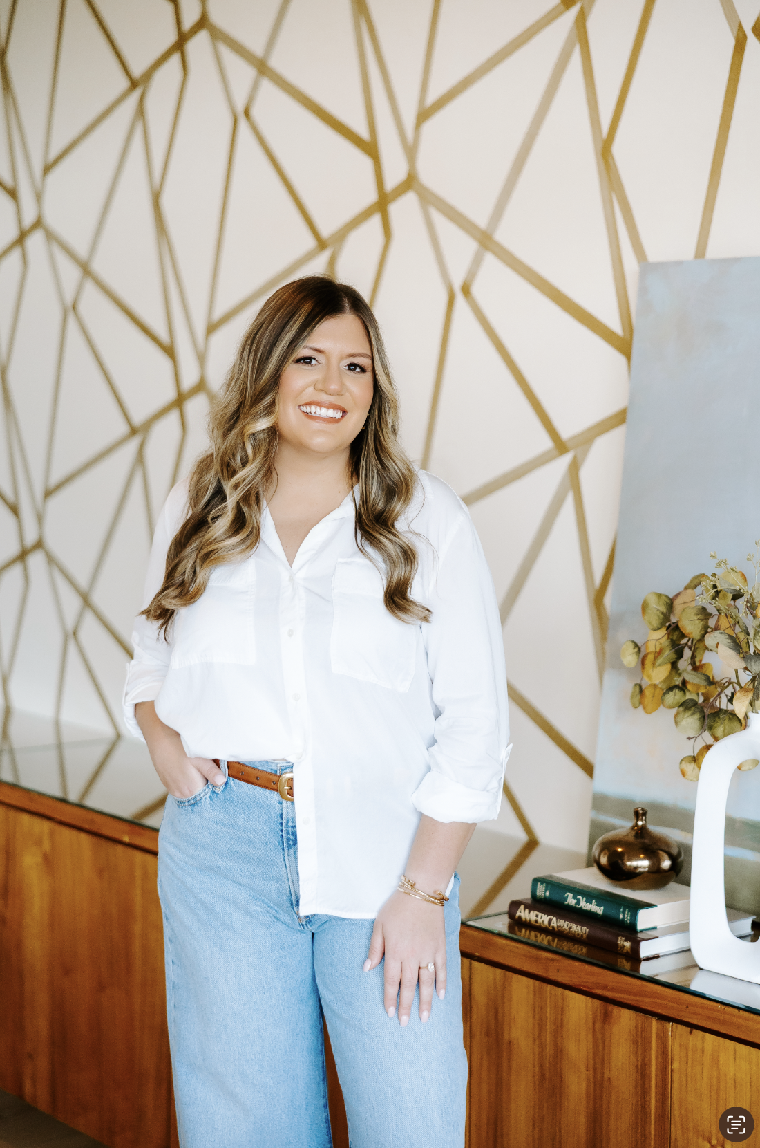 Heather Gorr, LPC-S, trauma-informed therapist and clinical supervisor based in Austin, Texas | Woman with dark curly hair standing smiling with one hand in her pocket, wearing a white shirt and blue jeans