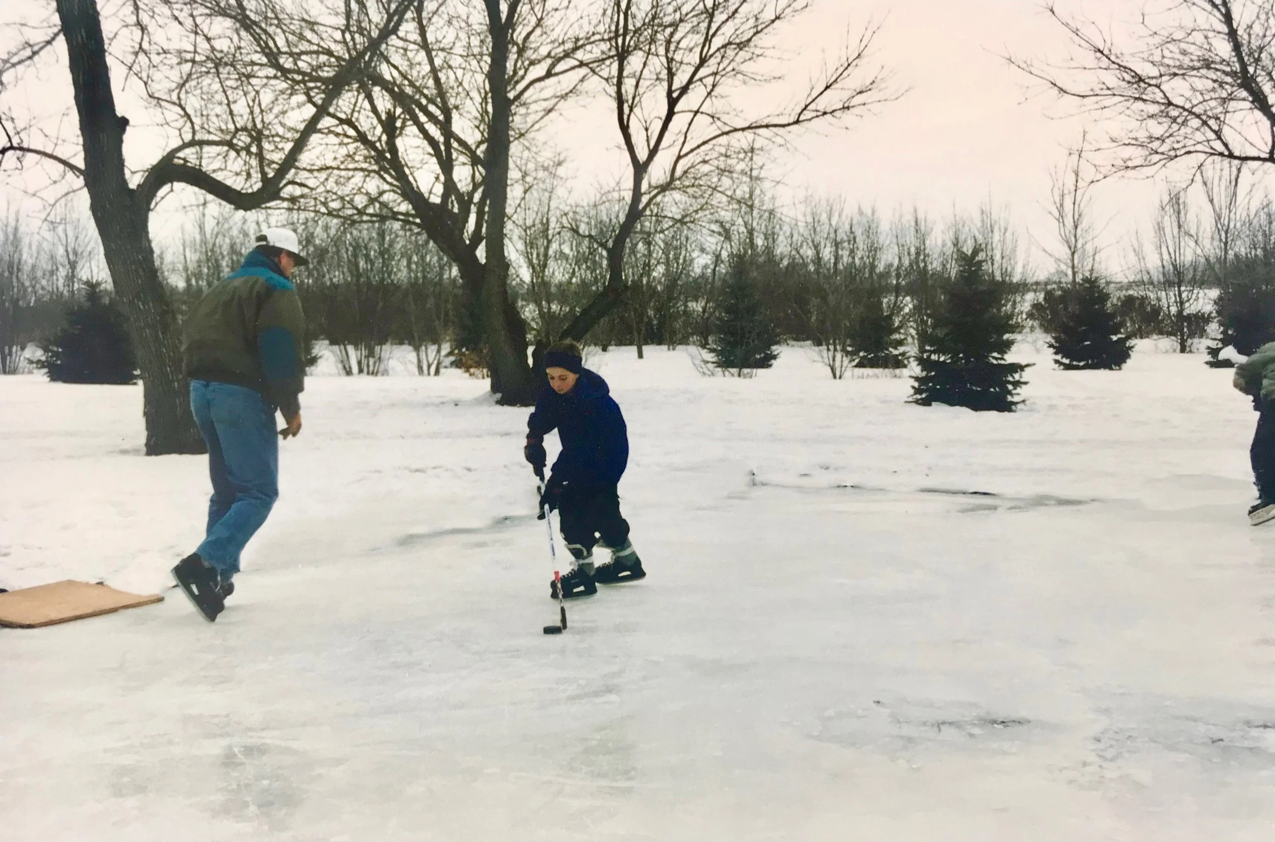 Son and dad skating on an outdoor ice rink