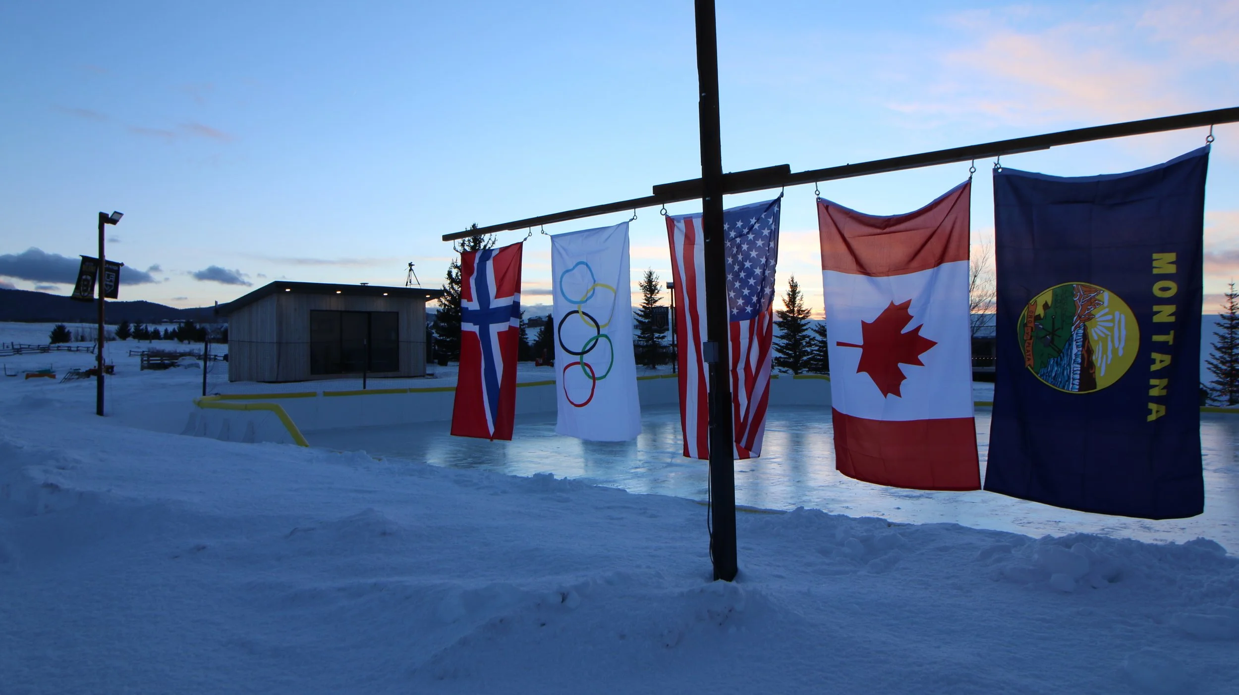 Picture of Norway, Olymplic, USA, Canadian, and Montana flag on back of rink