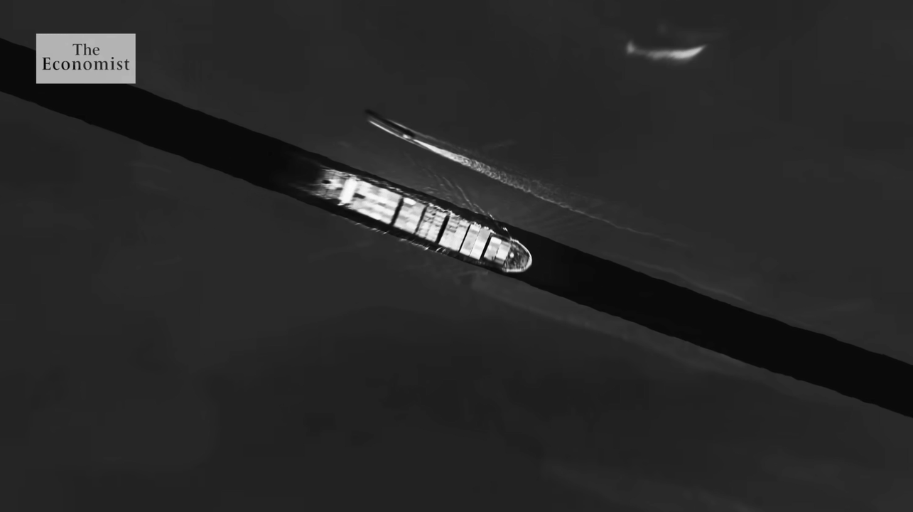 A black and white aerial photograph showing a car driving on a road, with a boat and a small boat behind it, and a crescent moon in the sky. "The Economist" logo is in the top left corner.