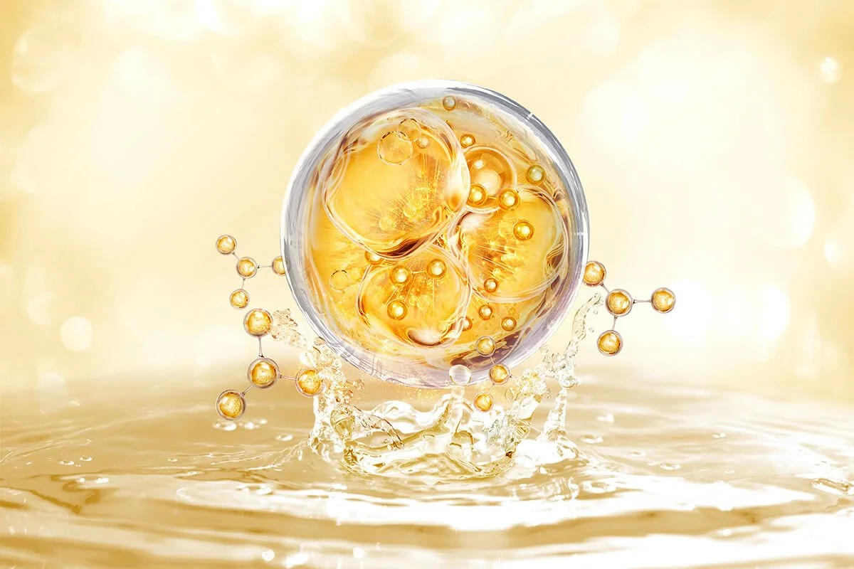 Close-up of a glass filled with a golden, bubbly liquid, possibly a beverage, with bubbles and splashes of liquid around it on a reflective surface.