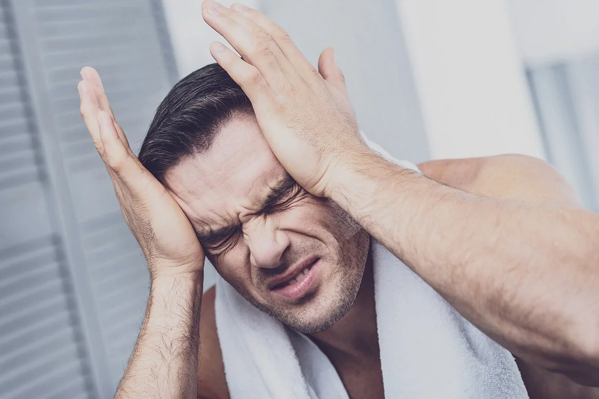 Man holding his head in pain, grimacing.