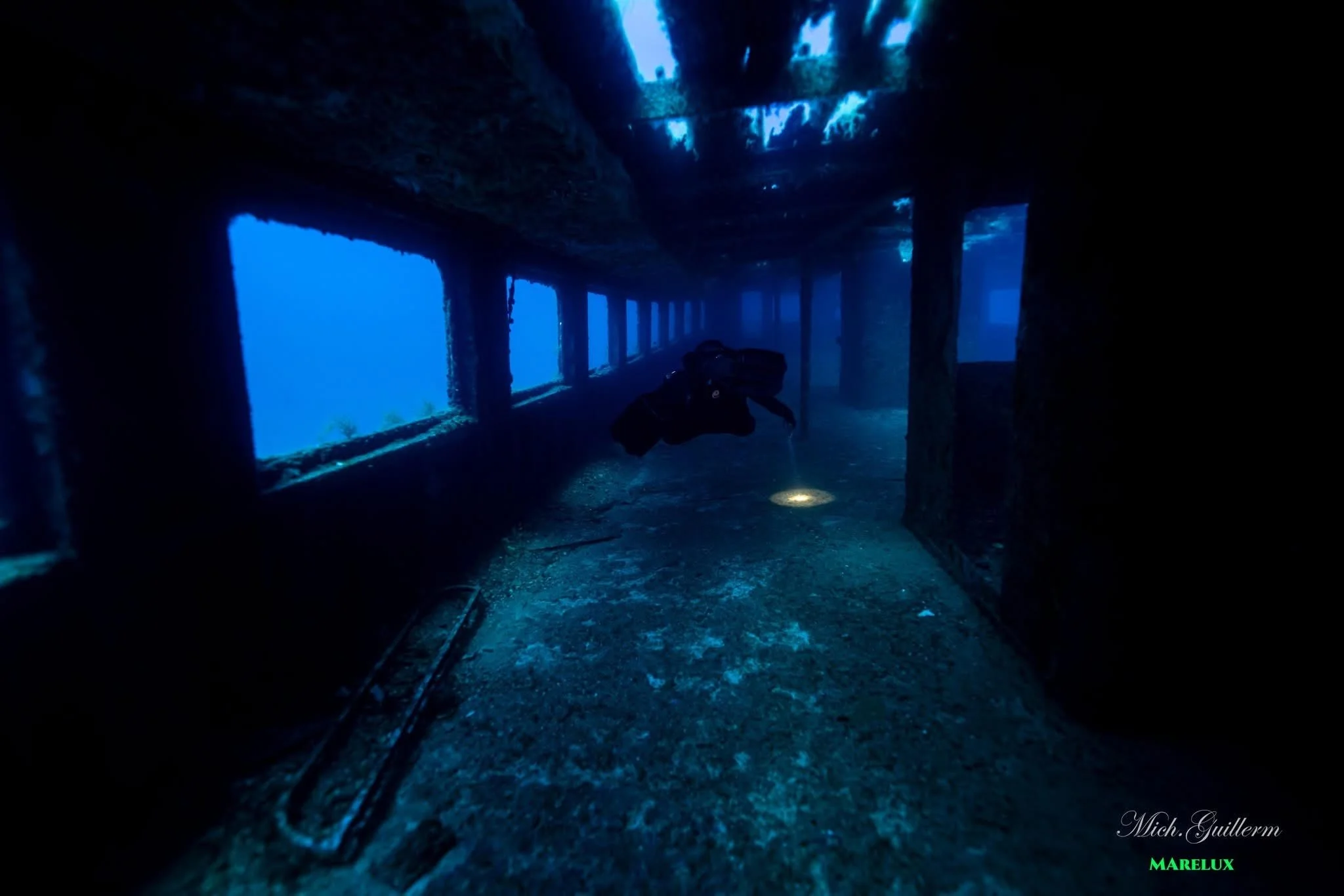 Une plongeuse explore l'intérieur d'une épave sous-marine mystérieuse, entourée d'eau bleue profonde. Instructeur de plongée privé, sud de l'italie dans les pouilles, épave