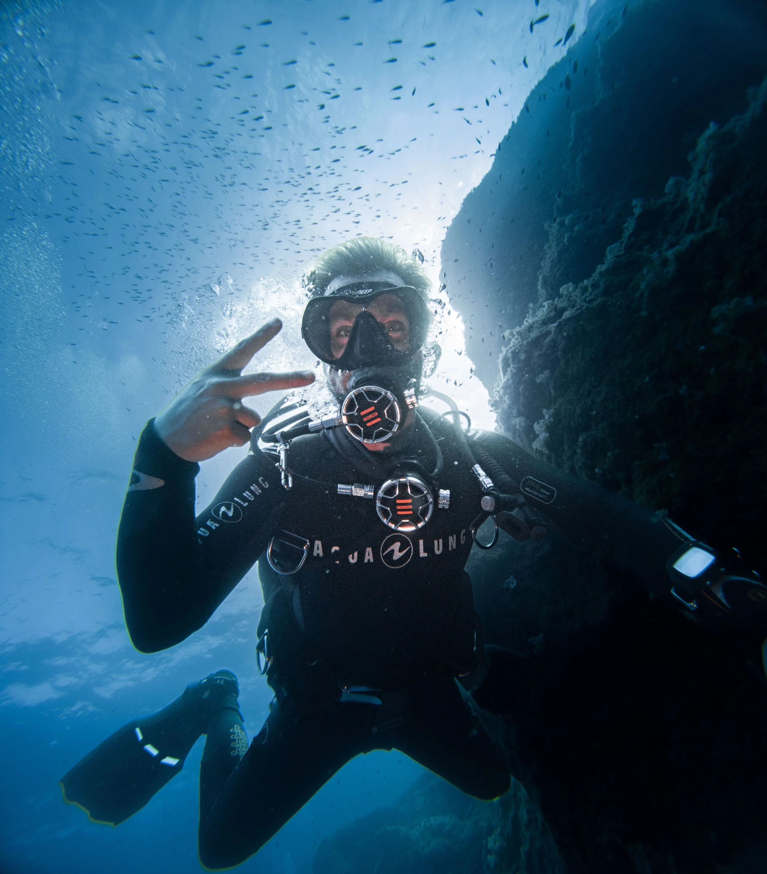 Plongée sous-marine avec un plongeur portant un équipement de plongée, nageant près d'une roche sous l'eau.
