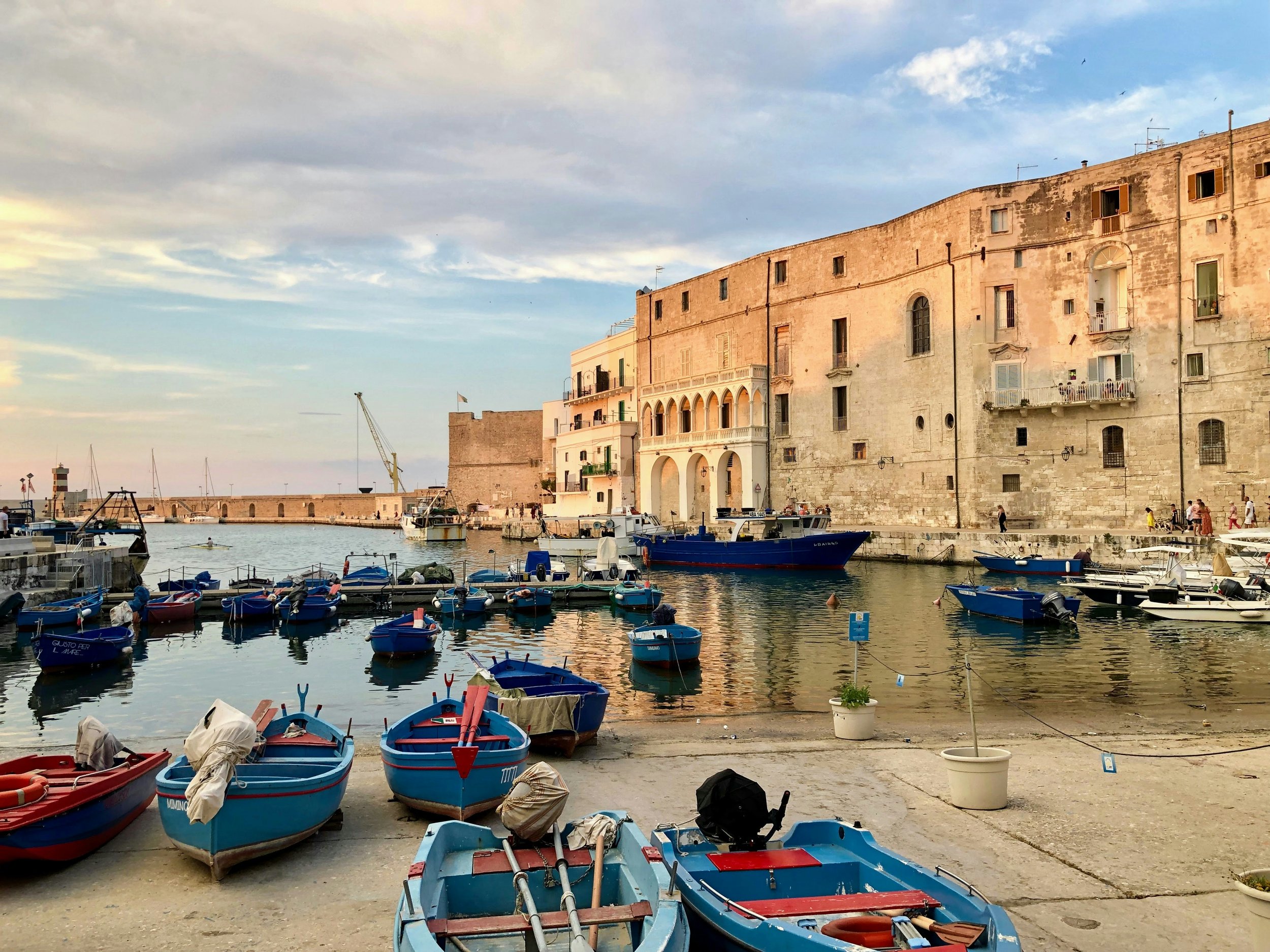 Port de mer avec des bateaux colorés et vieux bâtiments en pierre, au coucher du soleil. Italie du sud les pouilles