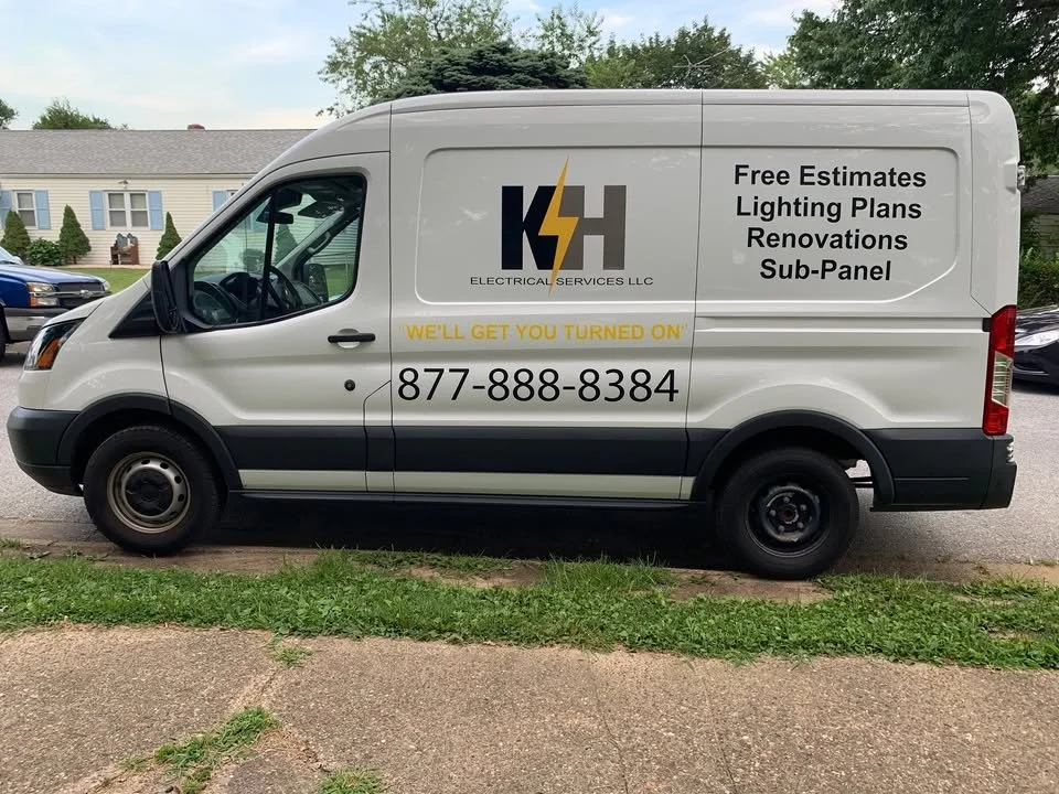 White commercial van with black and yellow logo for KSH Electrical Services LLC, advertising free estimates, lighting plans, renovations, and sub-panels, along with the phone number 877-888-8384 and the slogan "We'll get you turned on" on its side.