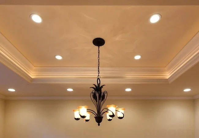 Ceiling with recessed lighting and a black chandelier with five lampshades.