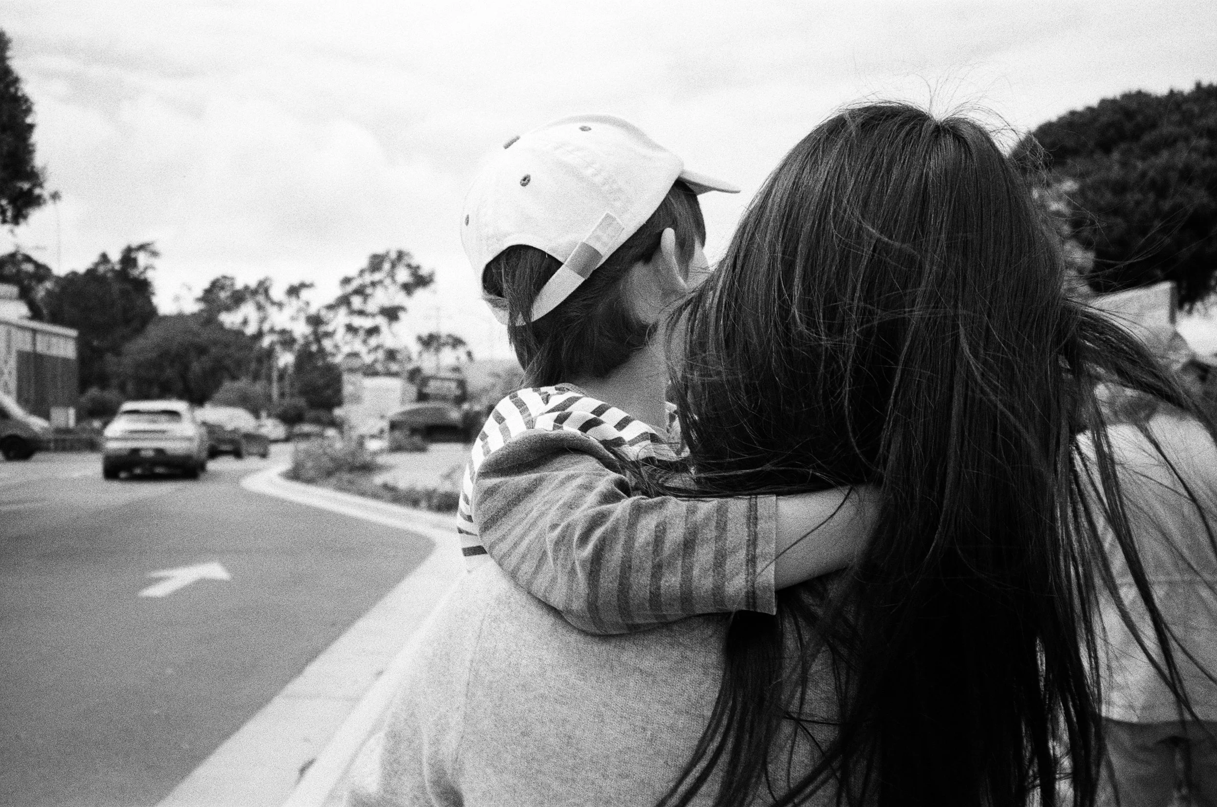 a black and white 35mm film photo of a mother holding her 5 year old son, their back is toward the camera. The photo was taken in Sausalito, California 