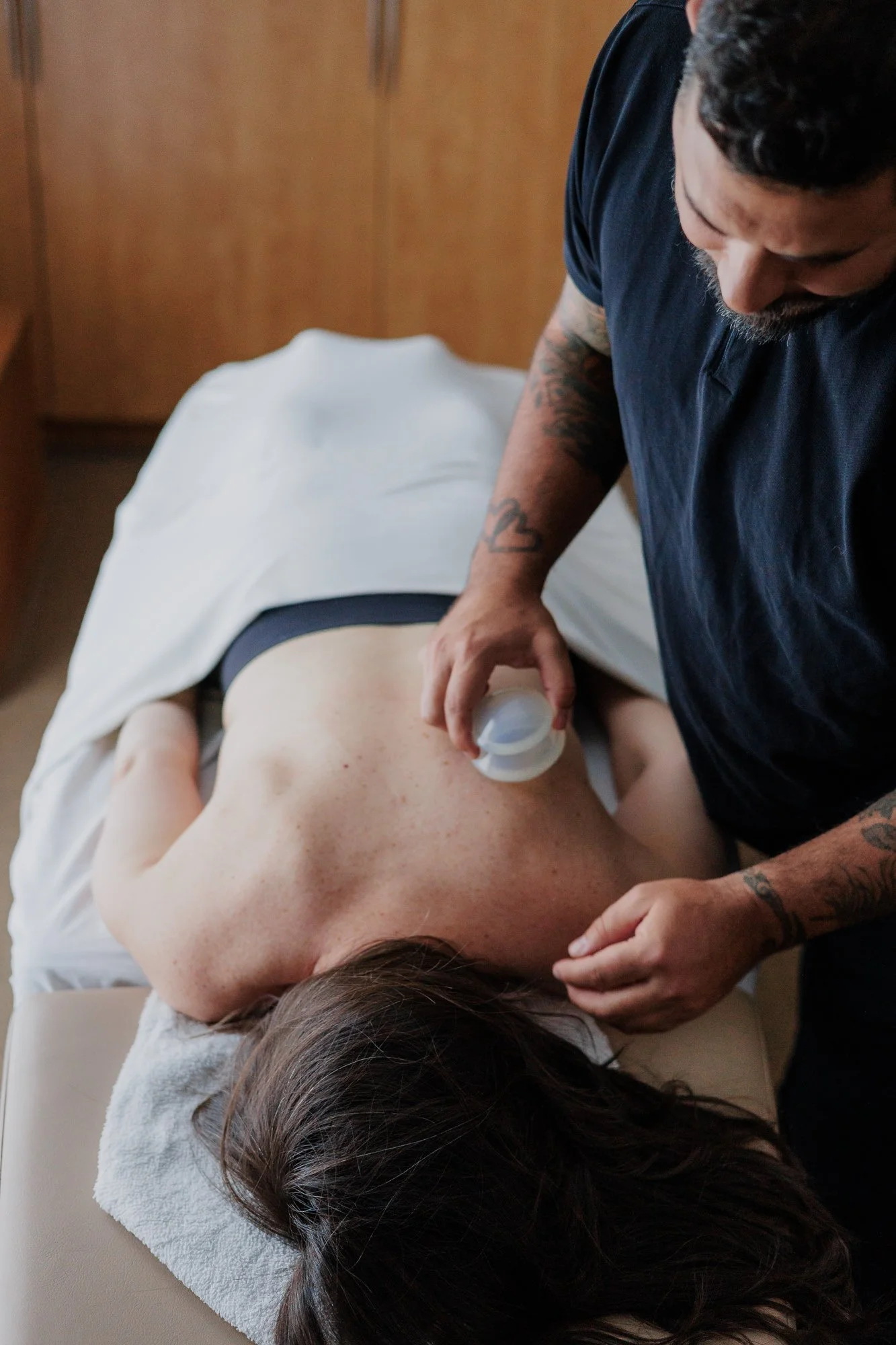 Acupuncturist performing cupping therapy on woman lying face down on a massage table