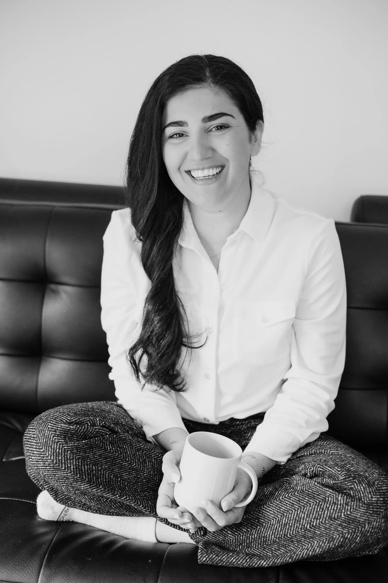 Girl or woman smiling naturally with a coffee mug sitting on a couch