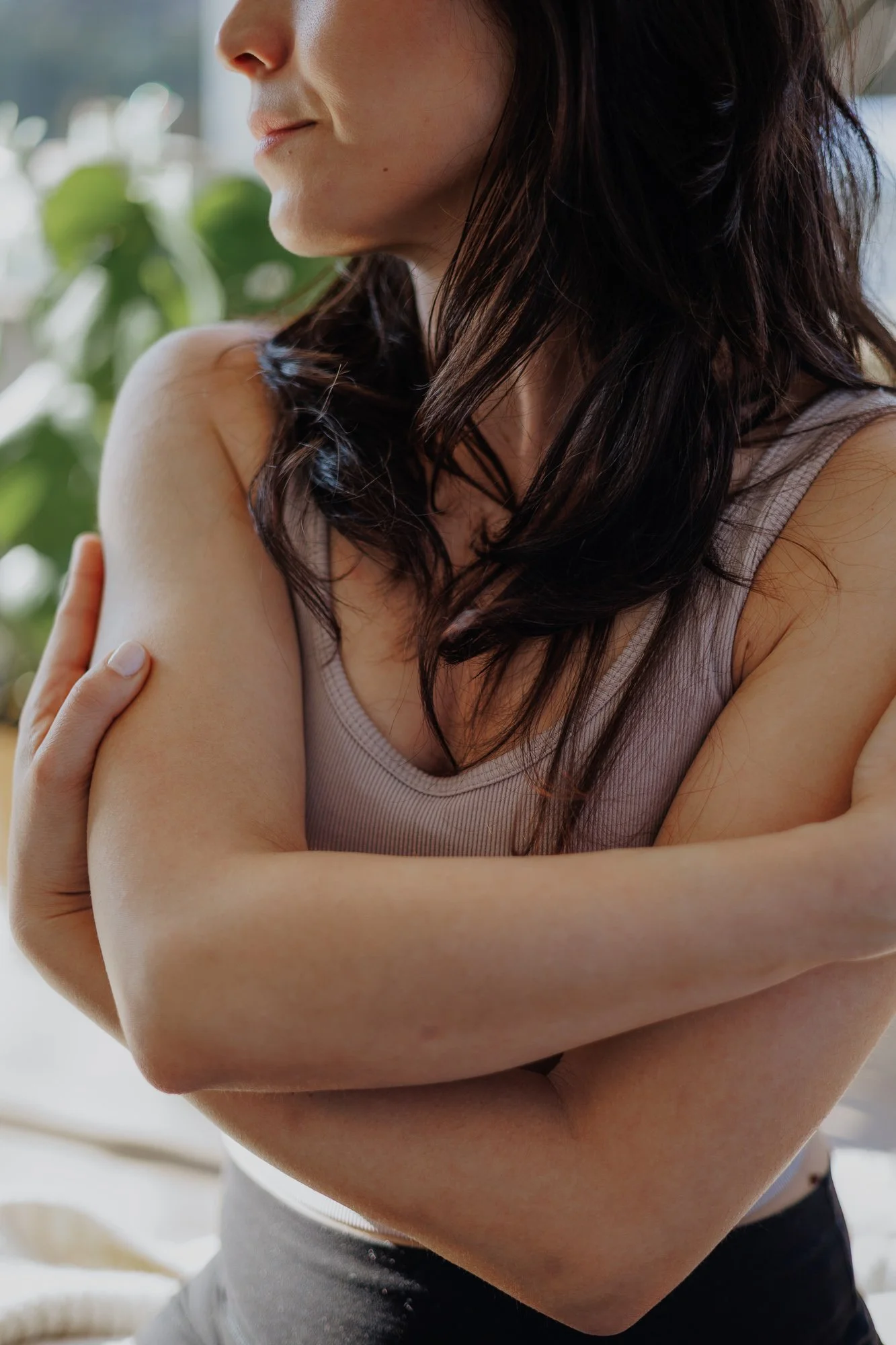 Close-up brand portrait of a woman with arms crossed, soft natural light by a window
